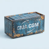 A blue metal storage box with white lettering, weathered rust-colored detailing, and a closed lid sits against a pale blue background.