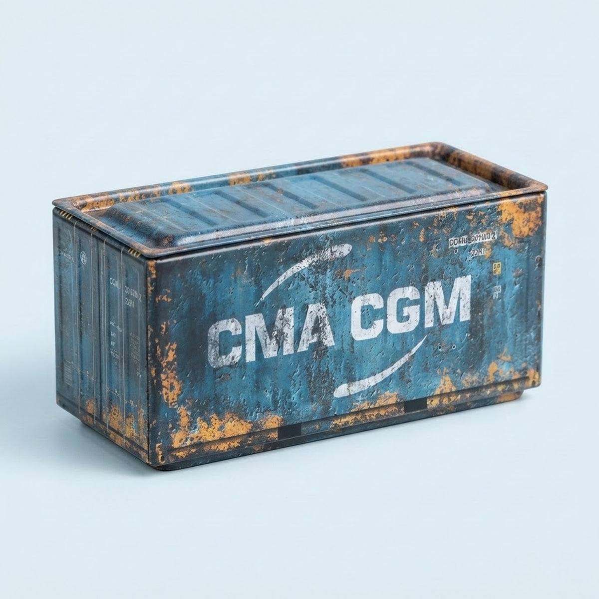 A blue metal storage box with white lettering, weathered rust-colored detailing, and a closed lid sits against a pale blue background.