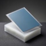 A stack of clear plastic protective sleeves or card cases, with one sleeve open and displaying a blue insert or backing, set against a dark gray background.