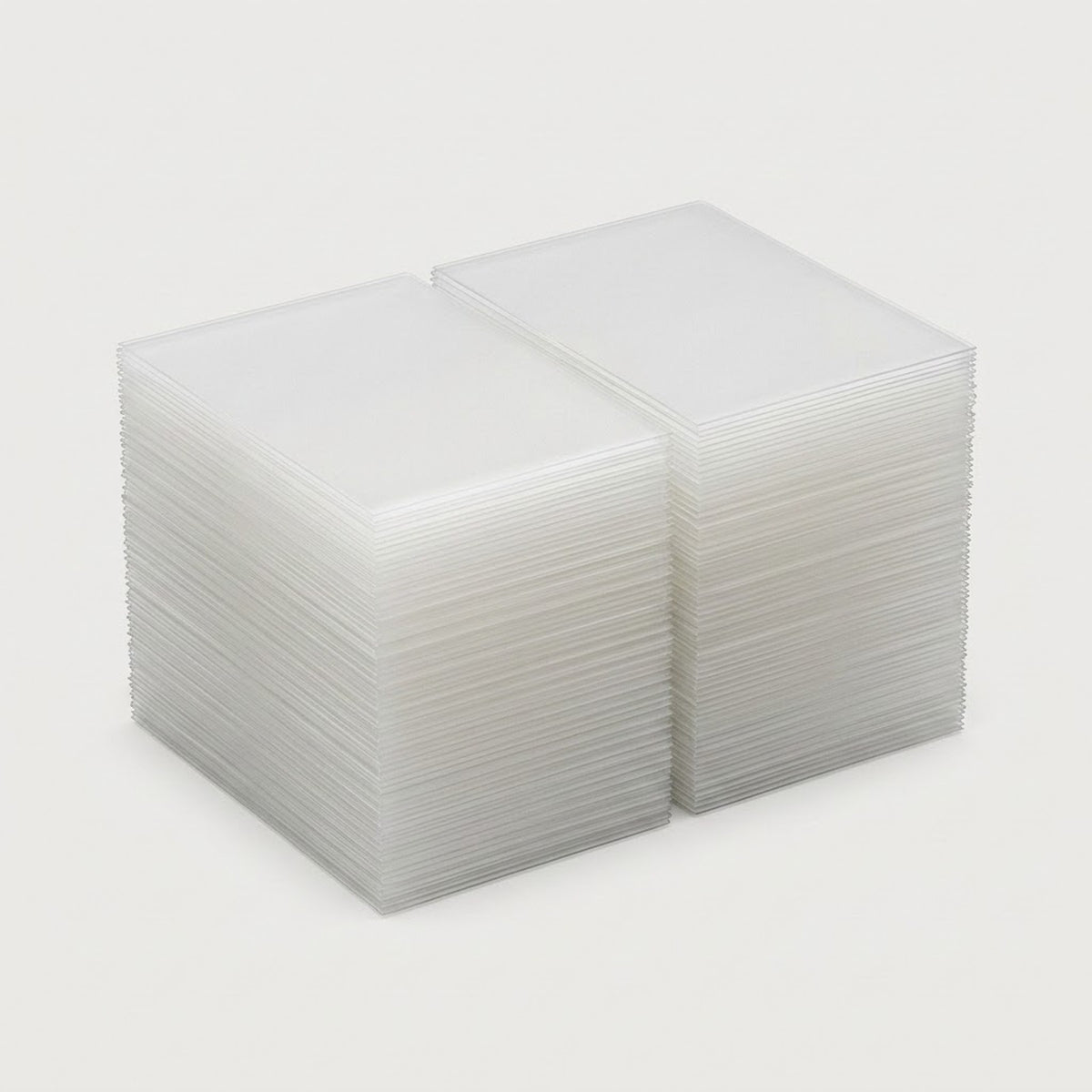 Two stacks of clear plastic card sleeves or protective cases, photographed on a clean light gray background.