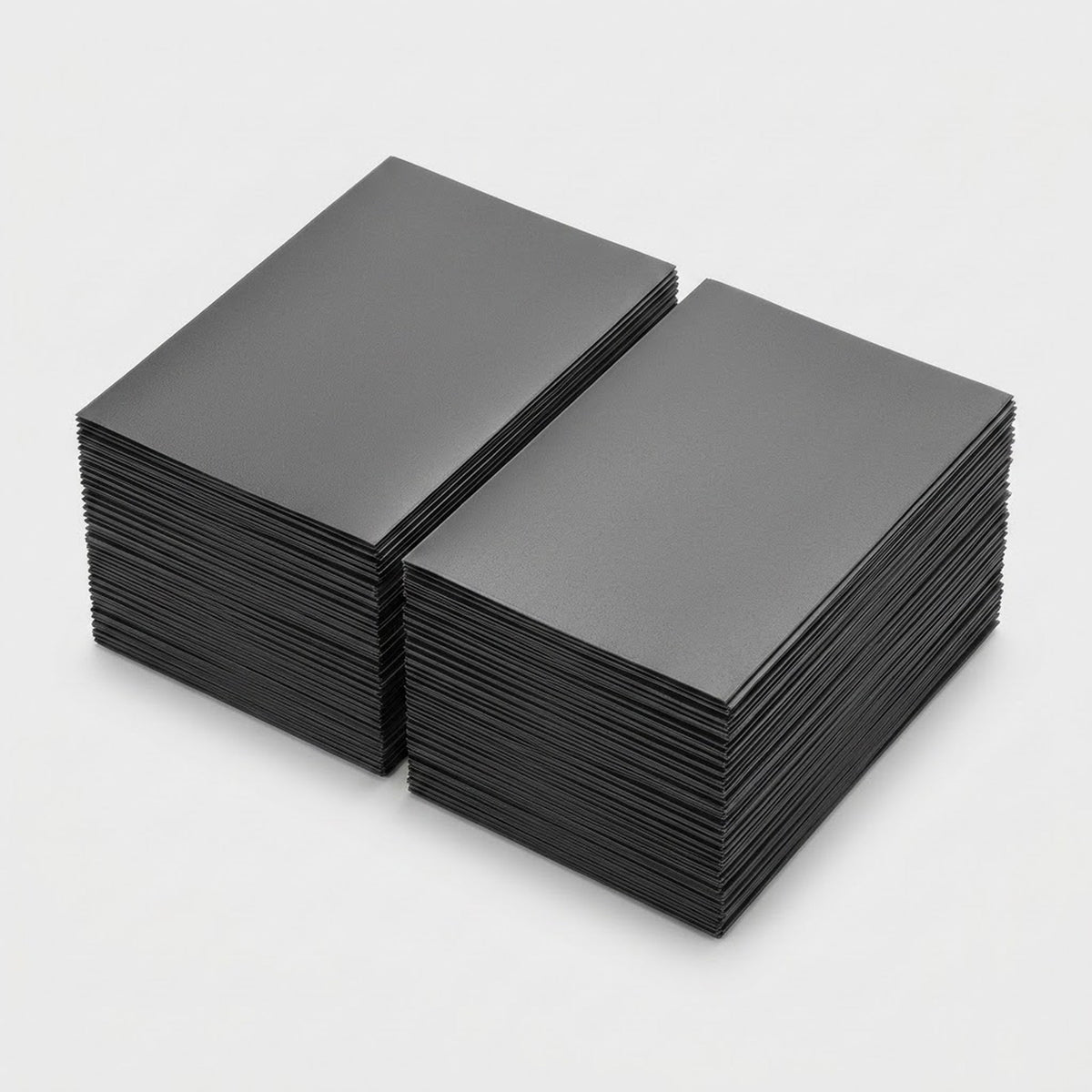 Two stacks of dark gray matte polypropylene card sleeves sit side by side on a light gray background.