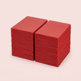 Two stacks of red matte polypropylene card sleeves sit side by side on a pale pink background.