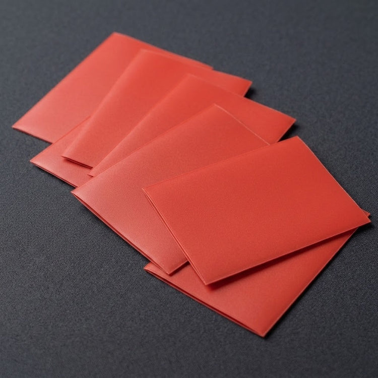 Red matte polypropylene card sleeves arranged in an overlapping fan on a dark gray textured surface.