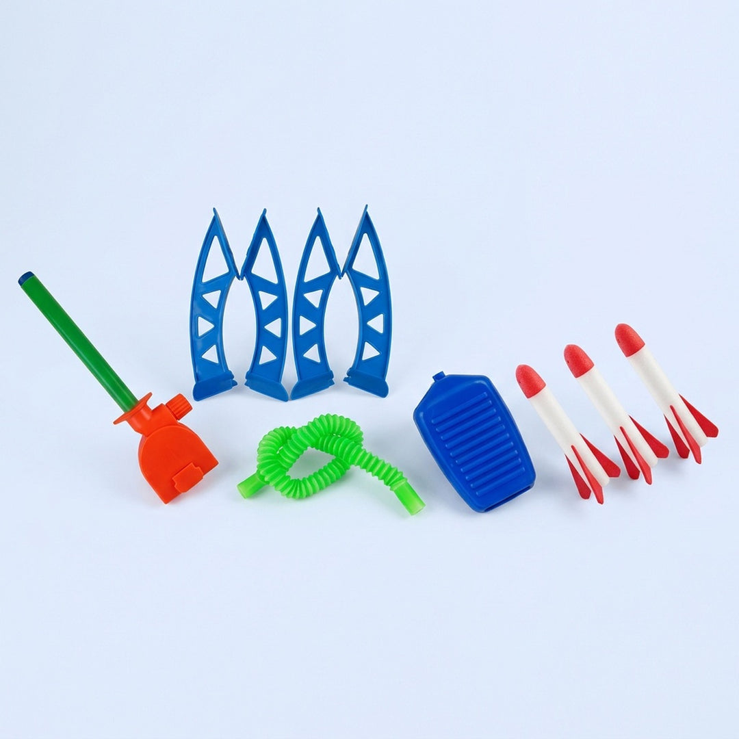 Unassembled rocket launcher with blue stand pieces, orange bracket, green tube and hose, blue foot pump, and three red-and-white rockets on pale blue.