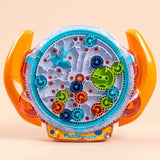 A colorful children's toy puzzle called 'Puzzle maze' with orange handles, a clear outer shell, and a white inner track featuring gears, wheels, and sliding pieces on a light beige background.