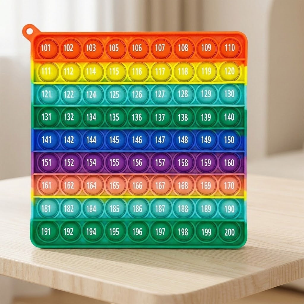 Rainbow silicone counting toy stands on a light wooden tabletop, displaying numbered bubbles against a softly blurred beige indoor background.
