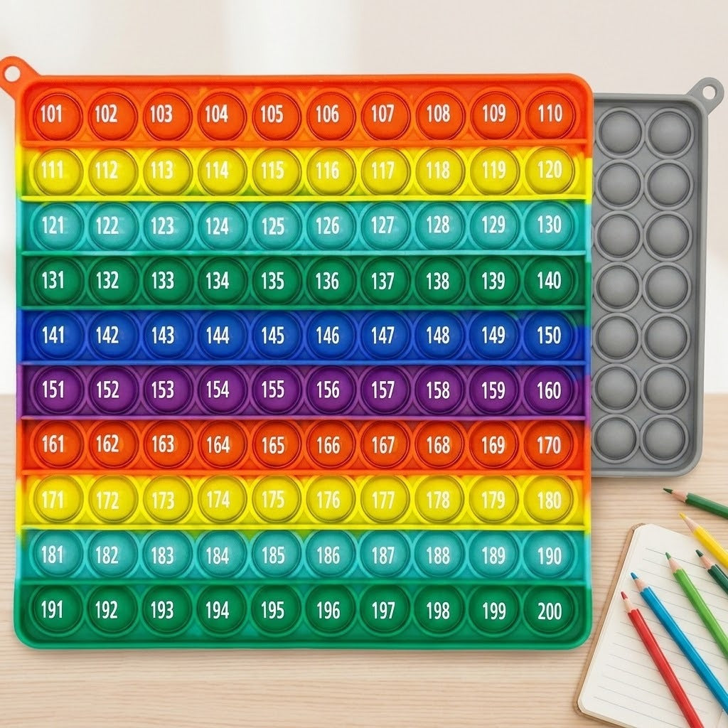 Rainbow silicone counting toy with bubbles numbered 101–200 on a wooden desk, beside colored pencils and a notebook, with a gray board behind.