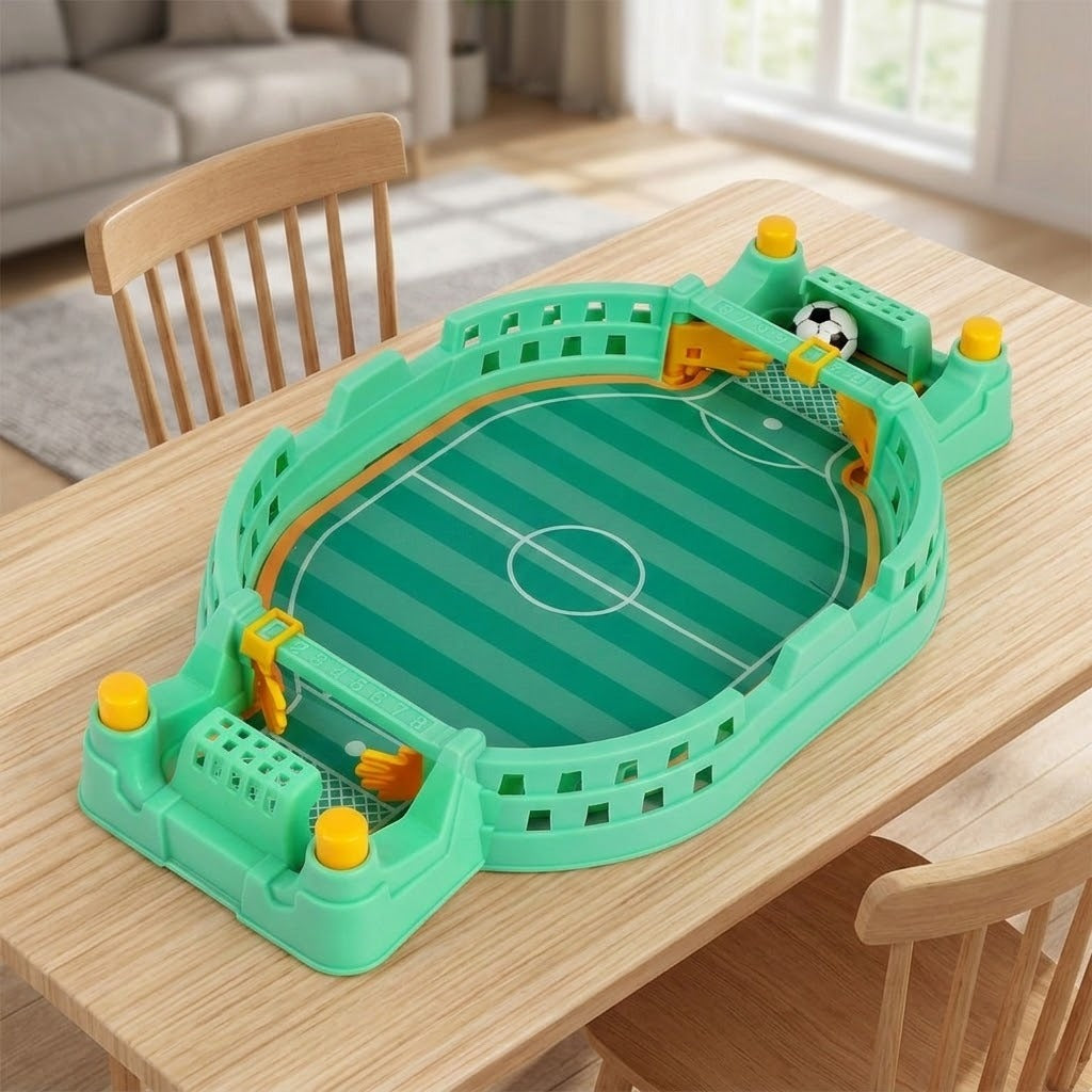 Green tabletop soccer game with yellow controls and a ball in the far goal on a wooden table between chairs.