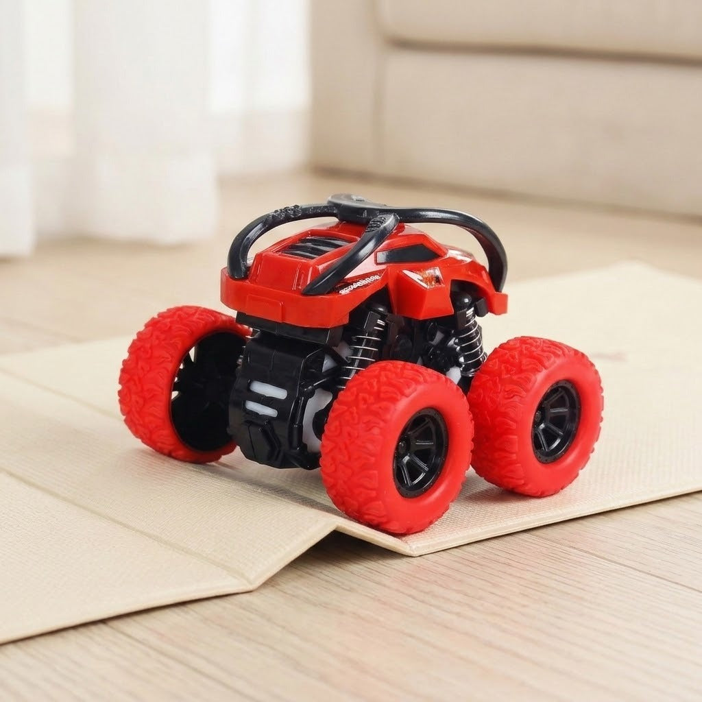 Red and black toy car with oversized red wheels rests on folded beige material over a pale wooden floor.