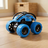 Blue and black toy car with oversized blue wheels sits on a wooden floor with a woven basket behind it.