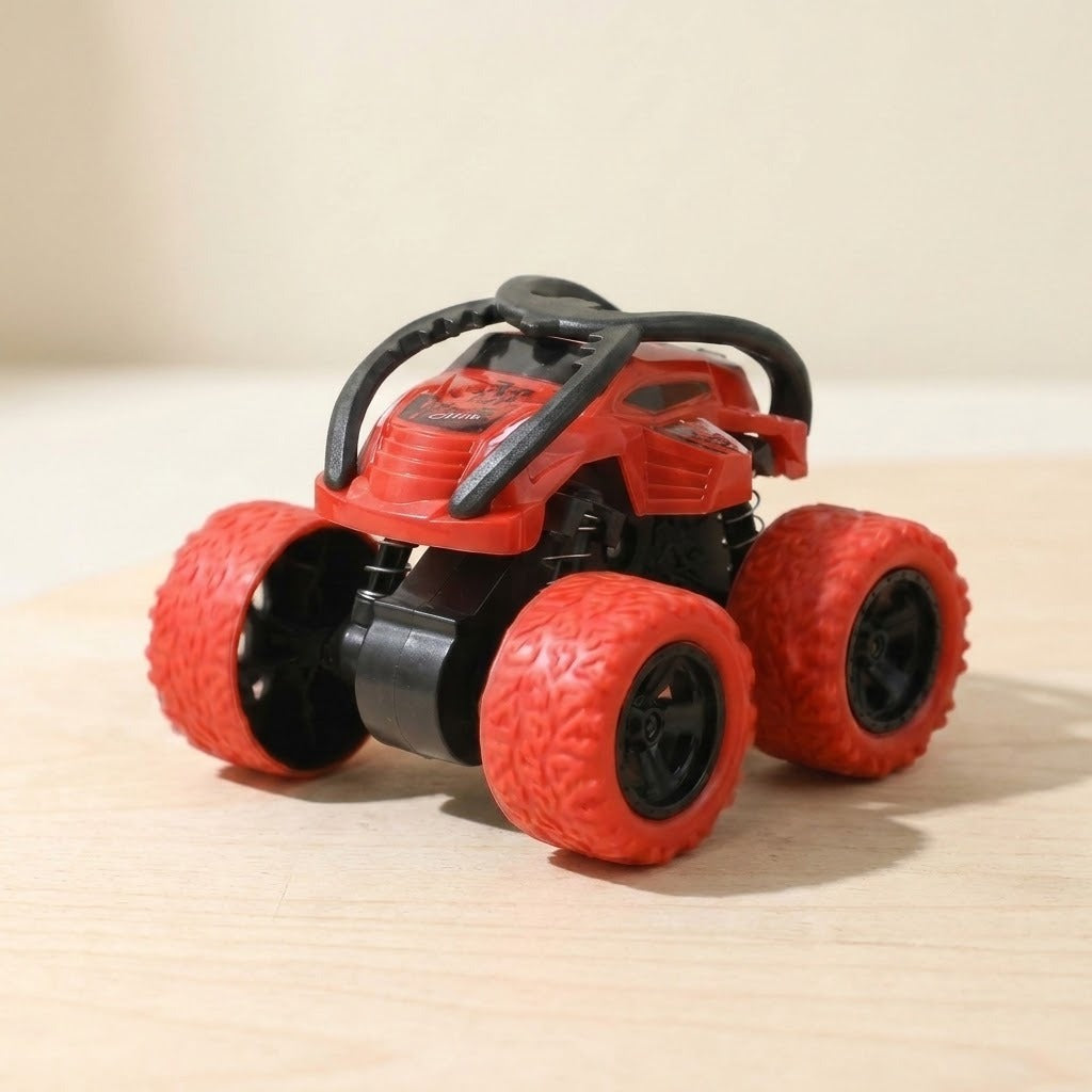 Red and black toy car with oversized red treaded wheels on a pale wooden surface against a cream background.