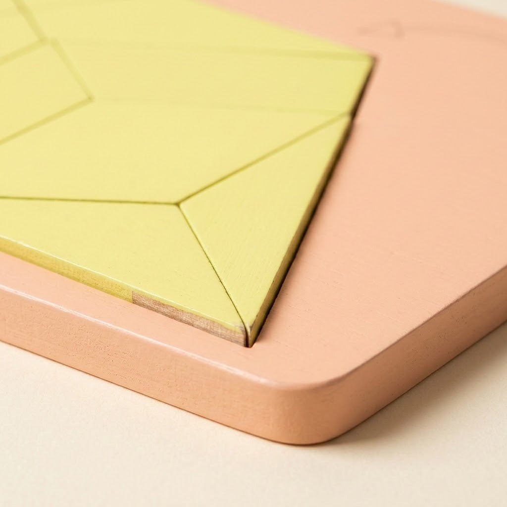 A geometric puzzle close-up shows pale yellow wooden pieces with exposed wood edges inside a peach tray with a rounded corner.