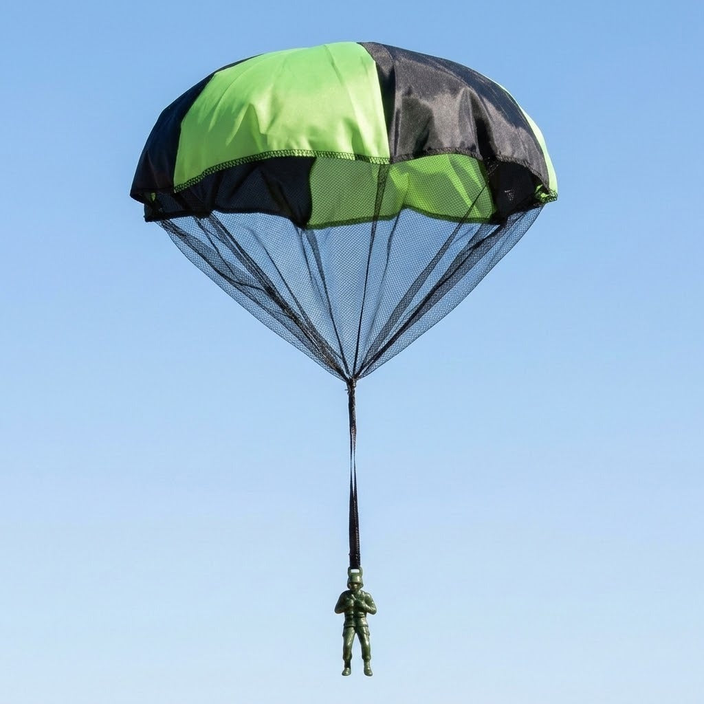 Green and black toy parachute with a black mesh skirt and a green plastic soldier hanging from a single strap, against a clear blue sky.