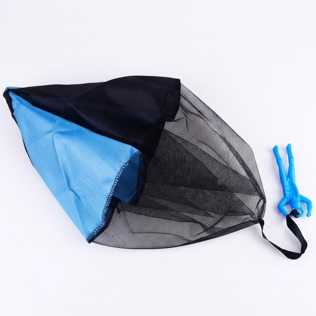 Blue and black parachute toy lies on a white surface, with its blue plastic soldier attached by a black strap.