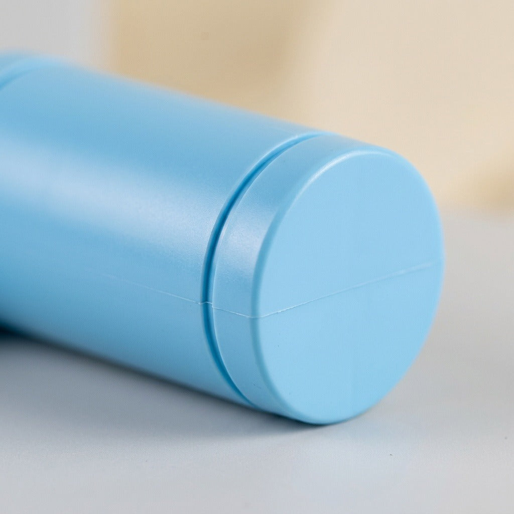 Close-up of the light blue water gun’s rounded cylindrical end resting on a gray surface against a blurred beige background.