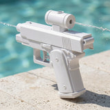 White water squirt gun with a cylindrical upper reservoir sprays water in opposite directions on pale paving beside a turquoise pool.