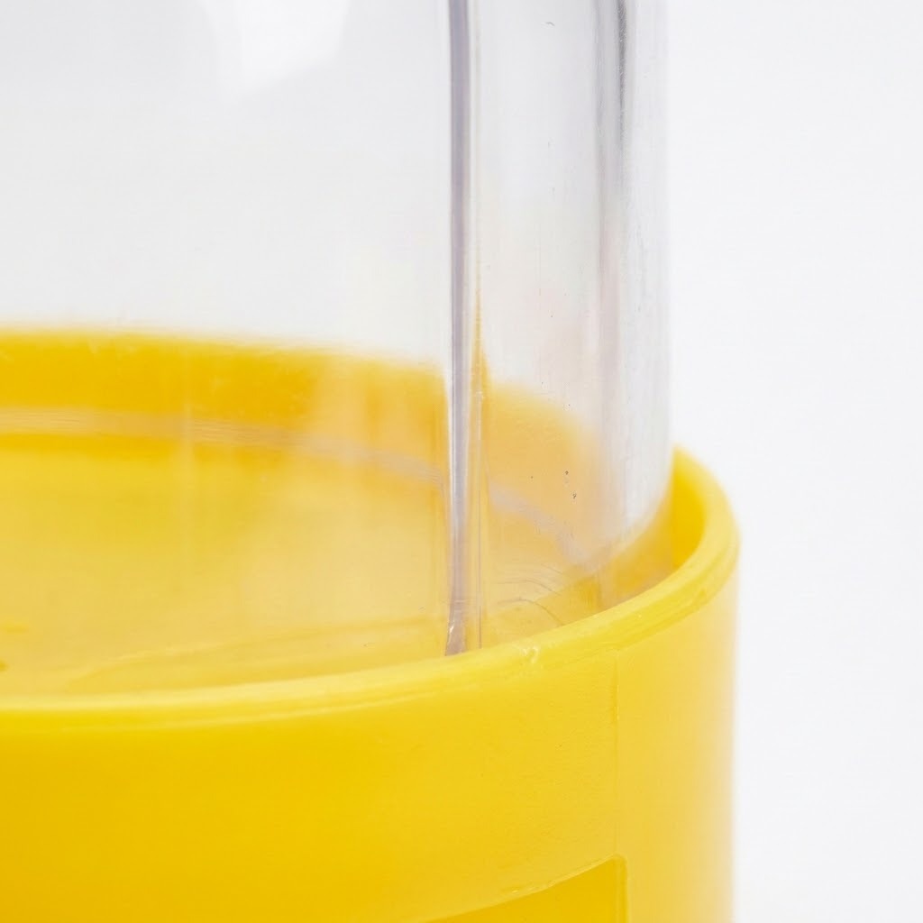 A close-up shows the clear plastic dome meeting the yellow base of a mini basketball game against white.
