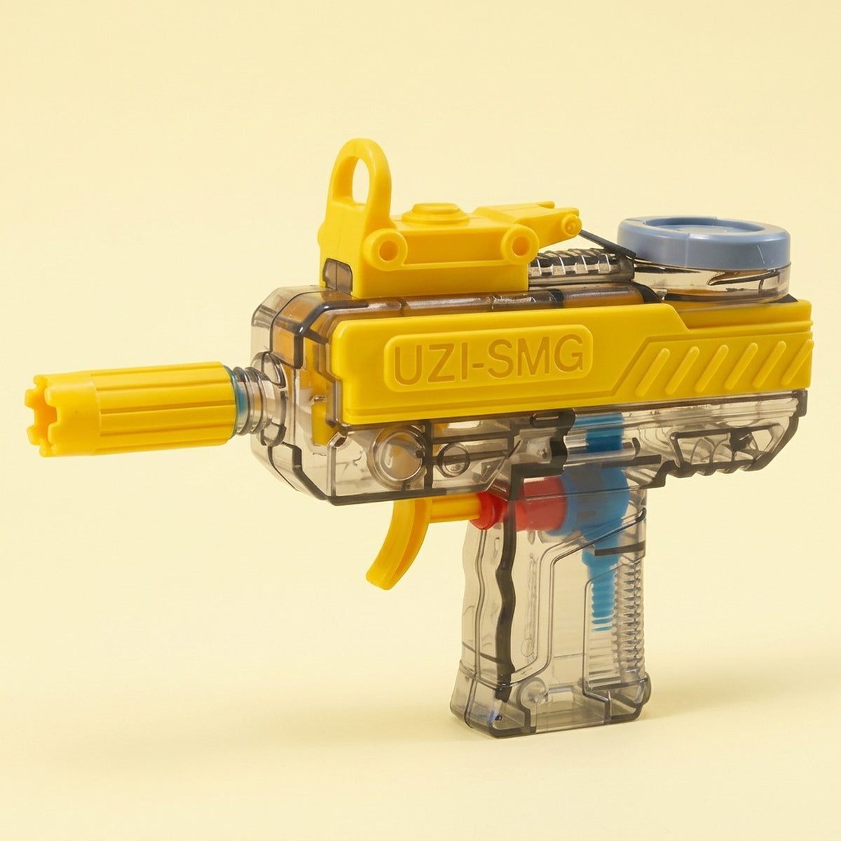 A yellow and transparent water gun stands against a pale yellow background, with a blue top cap and visible internal components.