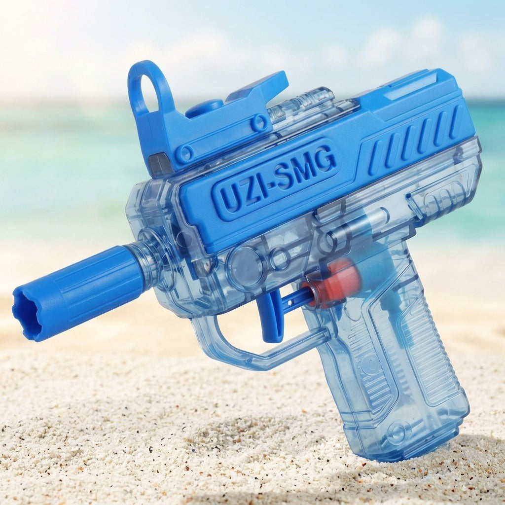A blue and transparent water gun tilts above sand, showing its blue trigger and internal components against a blurred beach background.