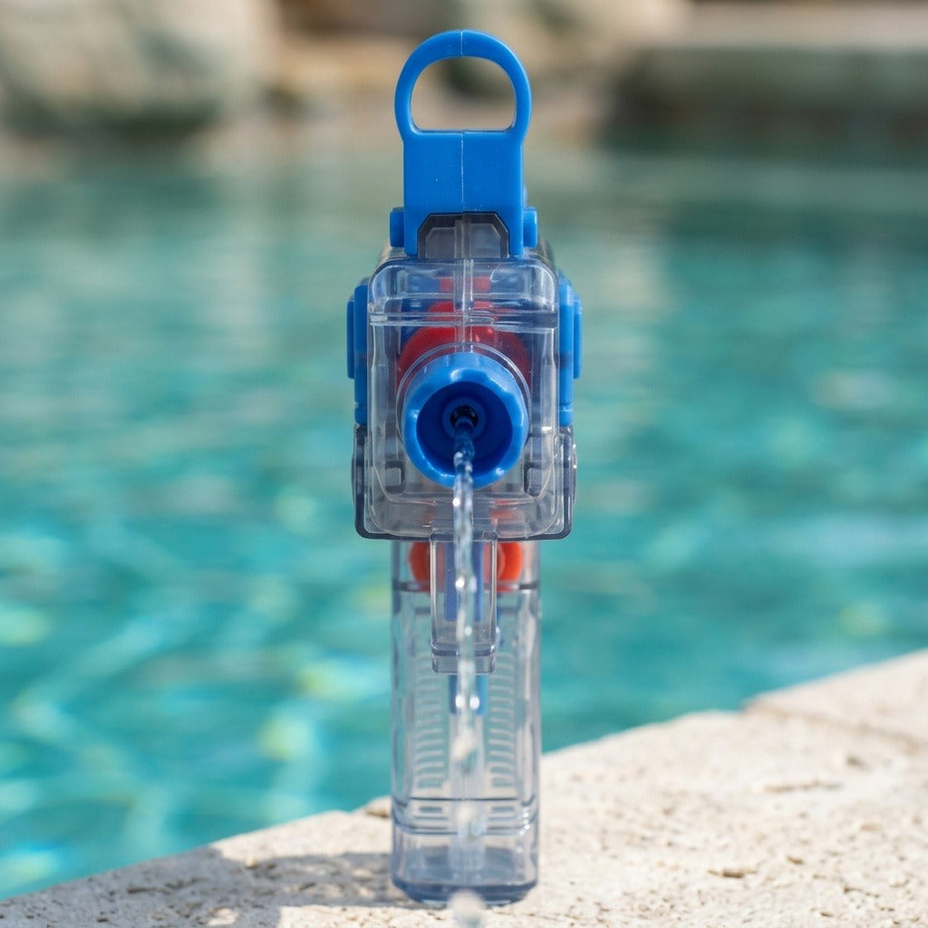 A blue and transparent water gun faces forward on a swimming pool edge, releasing a stream of water from its nozzle.