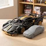 An assembled black and gold car building kit stands beside a smaller gray model car on a wooden table with display shelves behind.