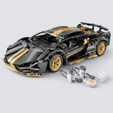 Black and gold car building kit stands assembled beside two wired motors and control components on a light gray background.