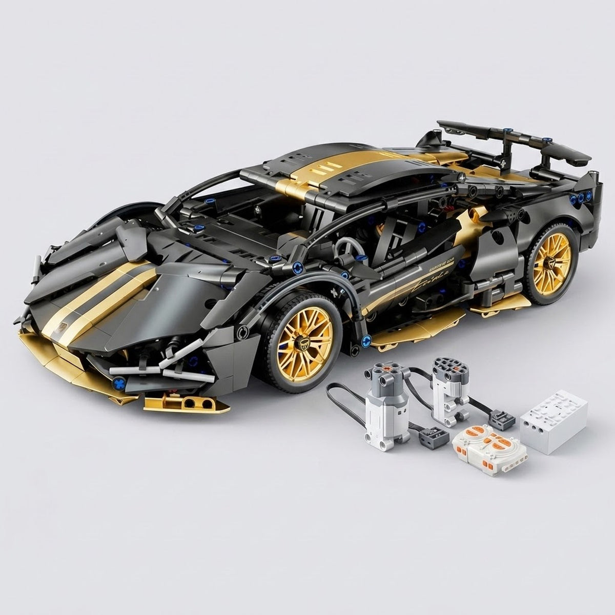 Black and gold car building kit stands assembled beside two wired motors and control components on a light gray background.