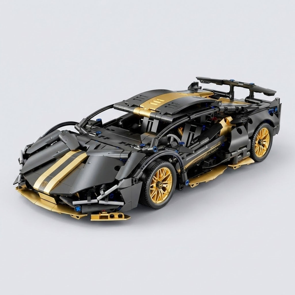 An assembled black and gold car building kit shows gold wheels, hood stripes, and a rear spoiler against a light gray background.