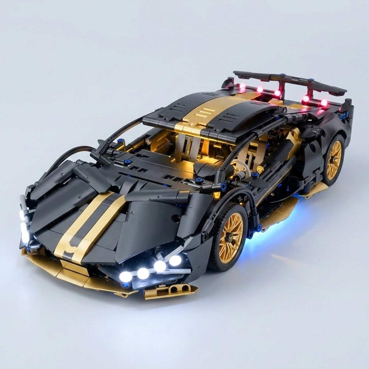 Assembled black and gold car building kit displays white headlights, red rear lights, and blue underglow against a light gray background.