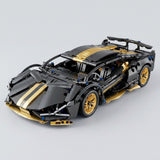 An assembled black and gold car building kit appears from a front three-quarter angle, with gold wheels and a spoiler against a gray background.