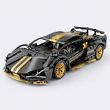 Black and gold car building kit shown assembled from a three-quarter angle, with gold wheels and rear spoiler against light gray.