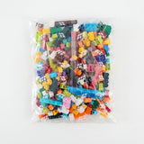 Colorful building blocks fill a clear bag printed with white block outlines against a white background.