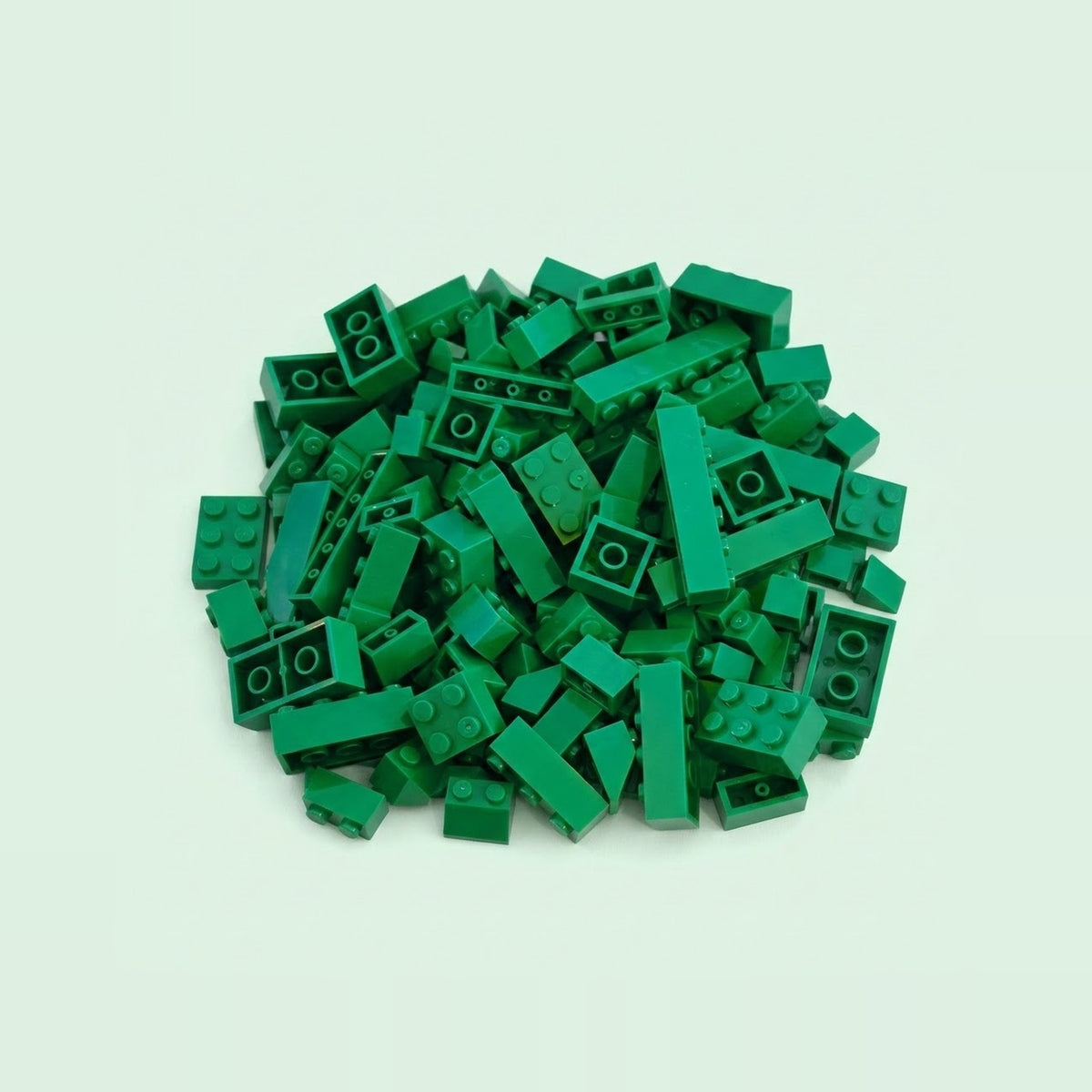 Dark green plastic building blocks in assorted rectangular sizes form a compact pile on a pale mint background.