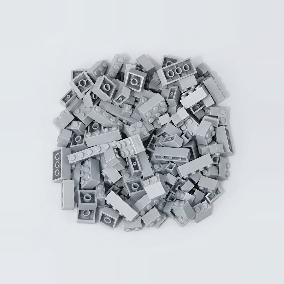 Light gray plastic building blocks in assorted sizes form a compact pile on a pale gray background.