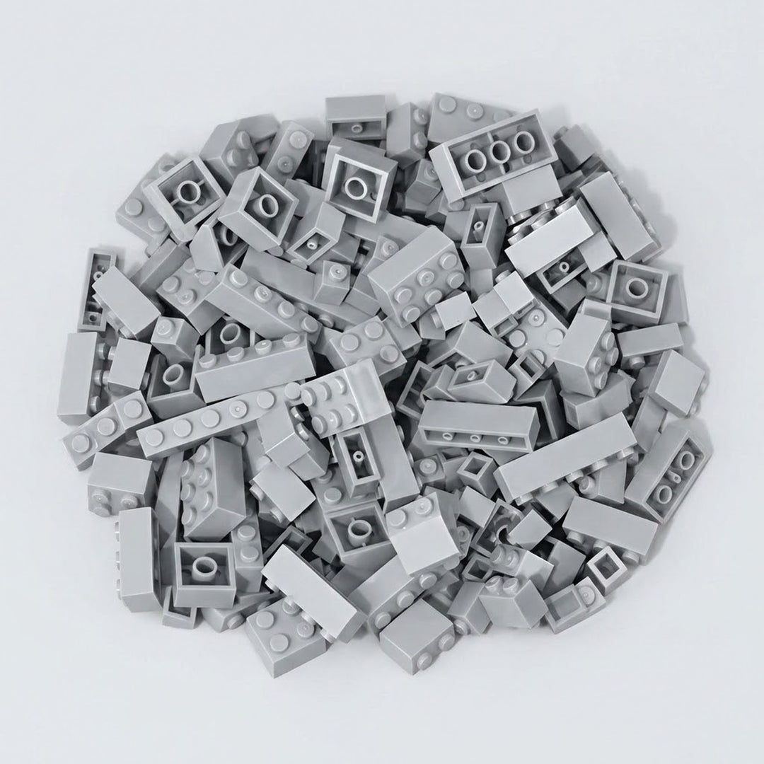 Light gray plastic building blocks form a broad pile with raised studs and hollow undersides visible on a pale gray background.