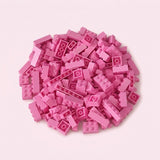 Pink plastic building blocks form a broad pile with raised studs and hollow undersides visible against a pale pink background.
