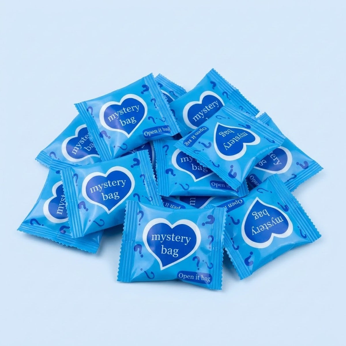 Blue blind bags for resin miniature figurines overlap in a pile on pale blue, with white-bordered heart labels and question marks.