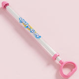 A pink and clear plastic hand-pump water gun toy with a pink trigger handle and pink nozzle, shown on a solid light pink background. The tube has 'WATER GUN' printed on it in blue and yellow.