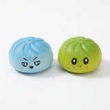 Blue and lime green steamed-bun squishy toys with cartoon expressions sit side by side against a white background.