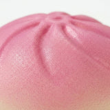 Close-up of a pink PU squishy toy showing its finely textured surface and pleated steamed-bun top against white.