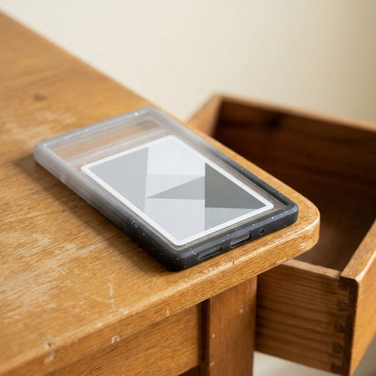 Black-gray slab bumper surrounds a clear slab containing a geometric card on a wooden desk beside an open drawer.