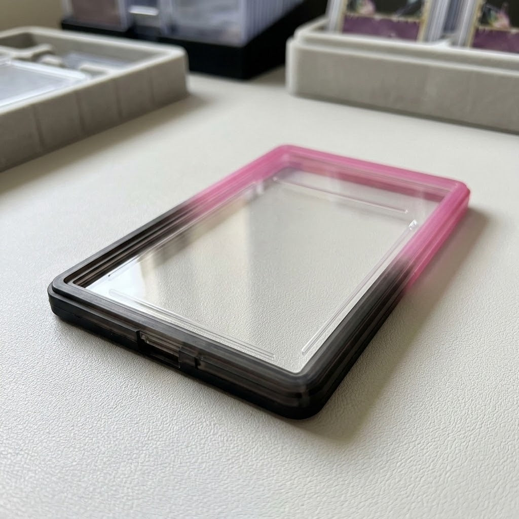 Pink-black slab bumper surrounds an empty clear slab on a light tabletop, with card storage trays blurred behind it.