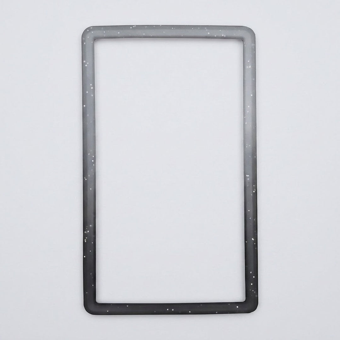 A speckled gray-to-black silicone TPU slab bumper lies flat on a light gray background with its open center visible.