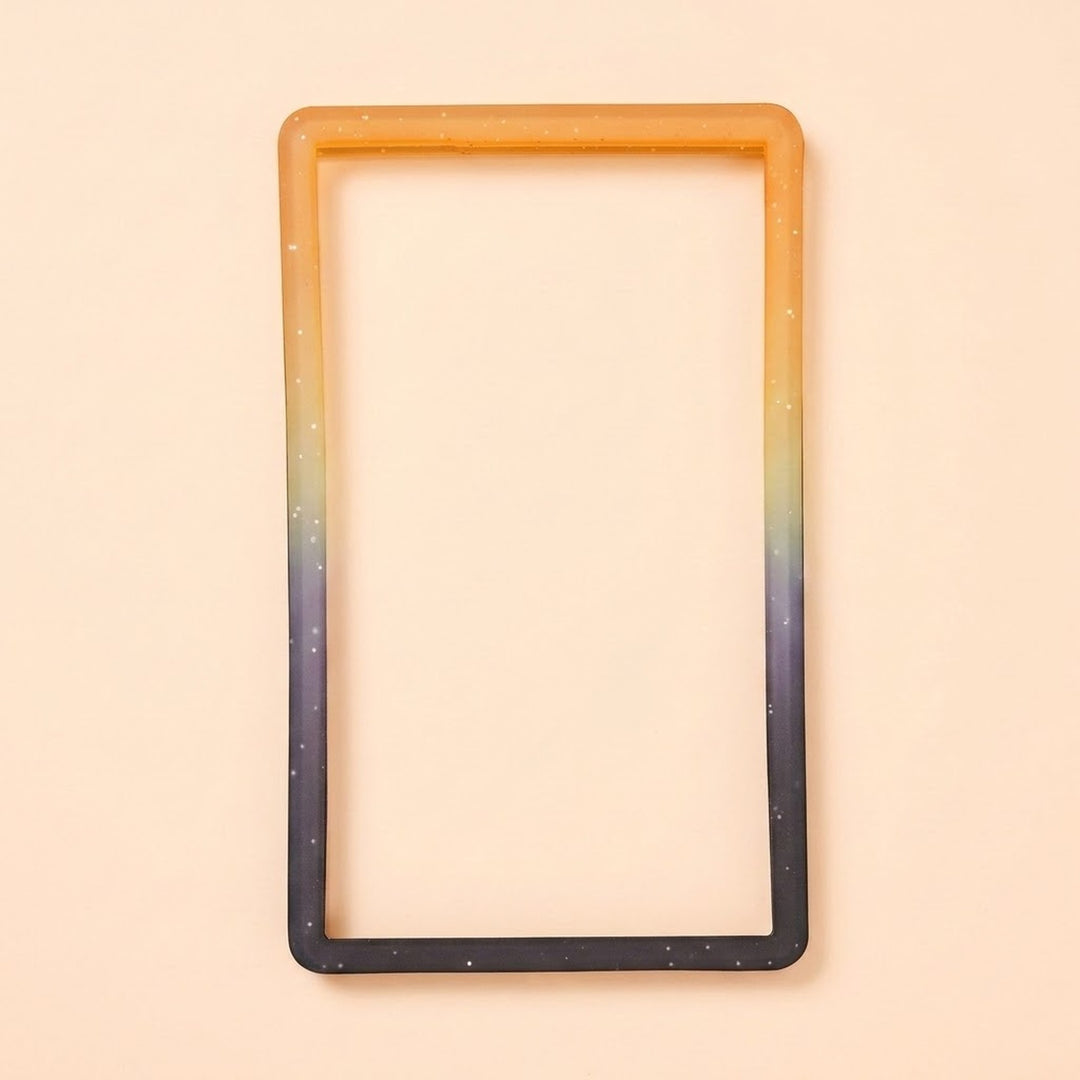 An orange-to-black silicone TPU slab bumper with white speckles lies flat on a pale peach background.