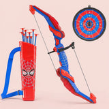 Red and blue toy archery set with suction cup arrows, web-patterned quiver and round hanging target against a pale pink background.