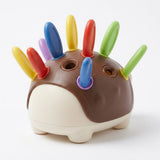 A colorful sensory toy shaped like a small hedgehog or creature, with a brown and cream body and multiple upright spikes in yellow, red, blue, green, and purple, photographed on a clean white background.