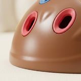 Close-up of the sensory toy’s brown shell shows red-rimmed holes and part of a blue rim against a cream background.