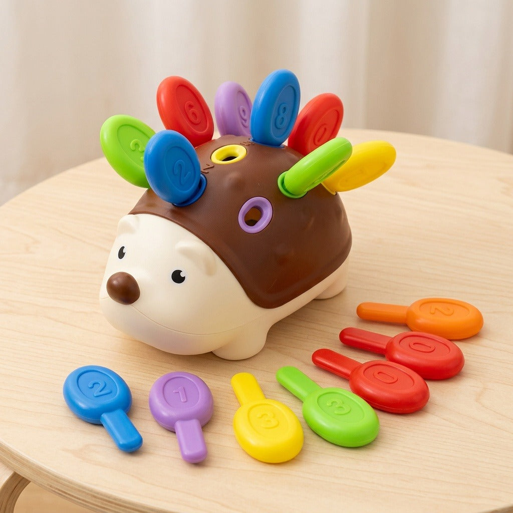 Brown and cream hedgehog sensory toy sits on a light wooden table with colorful numbered pegs inserted and arranged beside it.