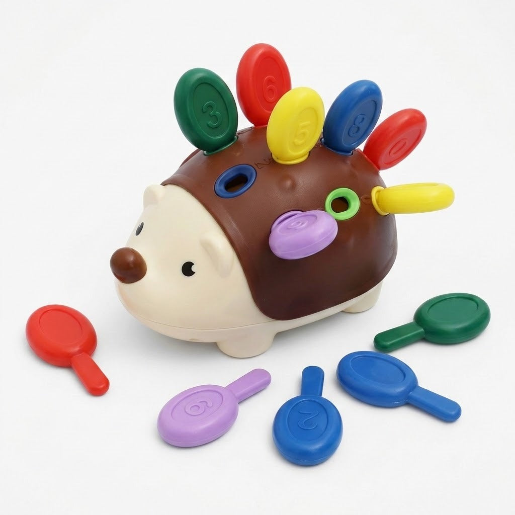 Brown and cream hedgehog sensory toy holds colorful numbered pegs, with loose pegs arranged around it on a white background.