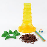Board game components on a white background: translucent yellow plastic tower, green palm leaves, brown monkeys, colorful sticks, and a die.